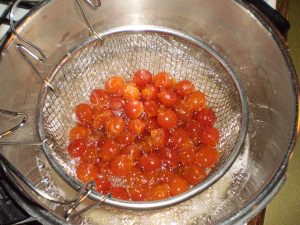 Früchte für kandierte Kriecherln im heißen Sirup versenken.